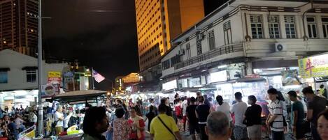 A crowded street at night with tall buildings and illuminated signs.
