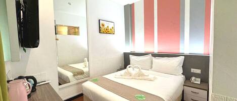 Quarto de hotel com cama, mesa de cabeceira, espelho e parede listrada.