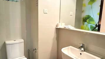 A bathroom with a toilet, sink, and mirror.