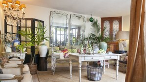 Een goed verlichte kamer met een kroonluchter, een grote spiegel en diverse planten.