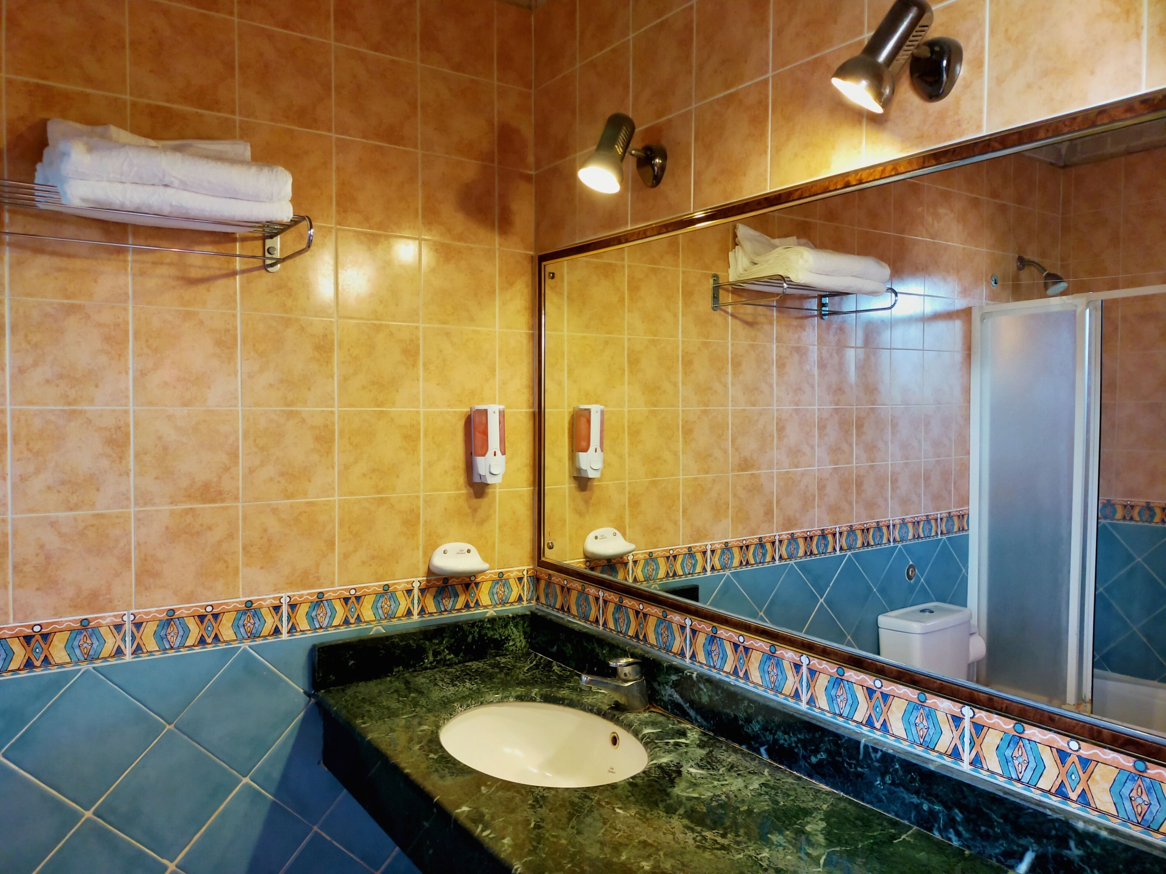 A bathroom with a sink, mirror, towel rack, and a shower.