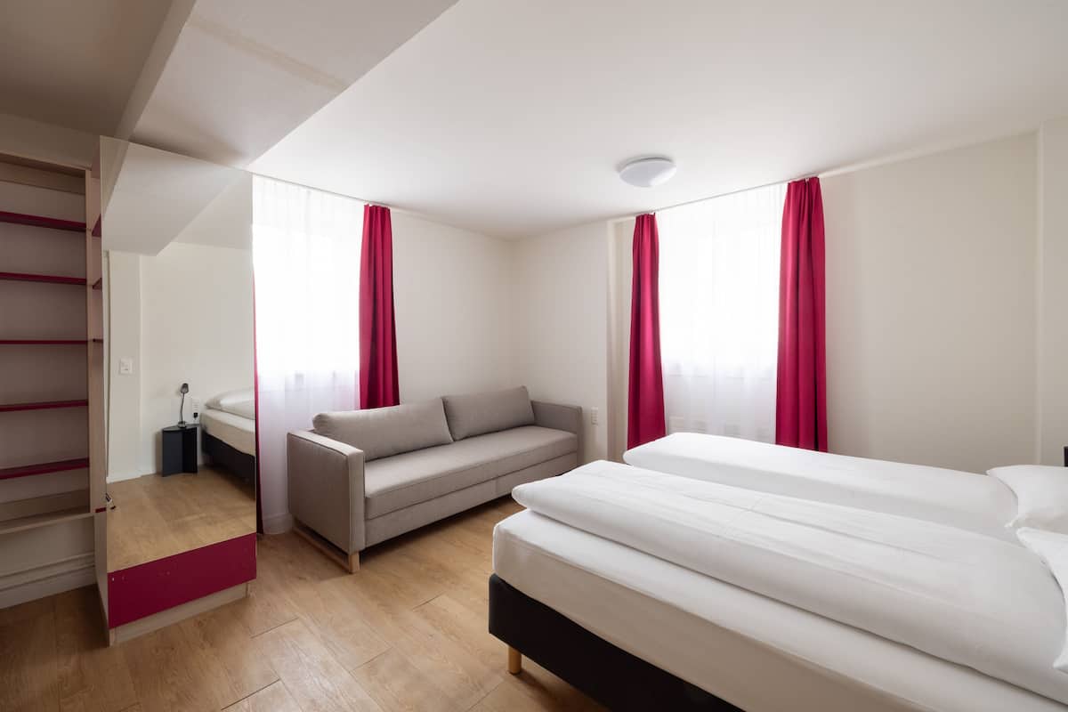 Ein modernes Schlafzimmer mit Bett, Sofa und Schreibtisch.