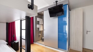 Una habitación de hotel moderna con cama, escritorio, televisor, baño y armario.
