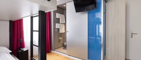 Une chambre d’hôtel moderne équipée d’un lit, d’un bureau, d’une télévision, d’une salle de bain et d’une armoire.