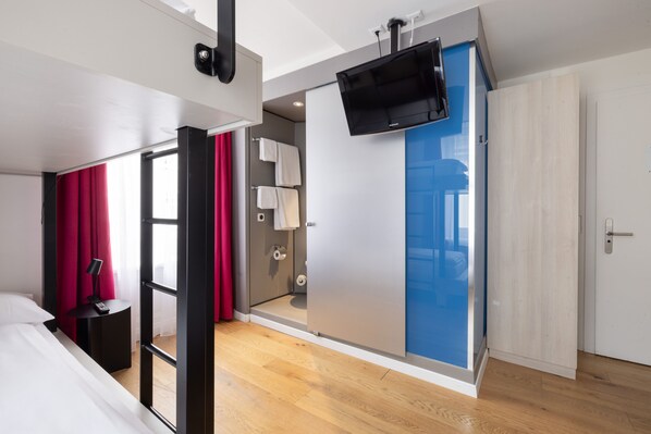 Una habitación de hotel moderna con cama, escritorio, televisor, baño y armario.