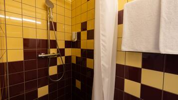 Une salle de bain avec des carreaux de sol aux motifs à carreaux jaunes et bruns, une pomme de douche et un porte-serviettes avec une serviette blanche.