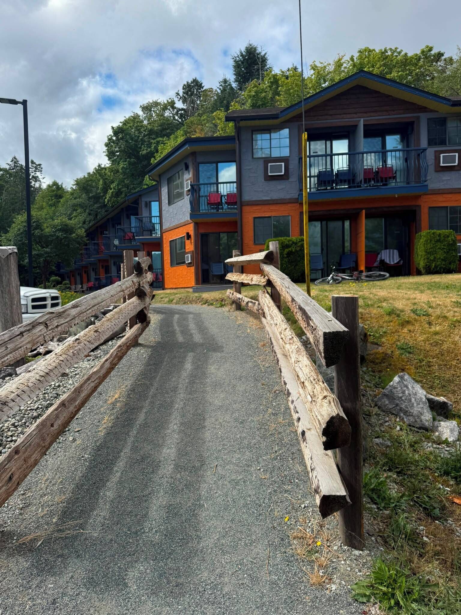 Un bâtiment moderne avec une allée incurvée, une clôture en bois et un véhicule garé à proximité.