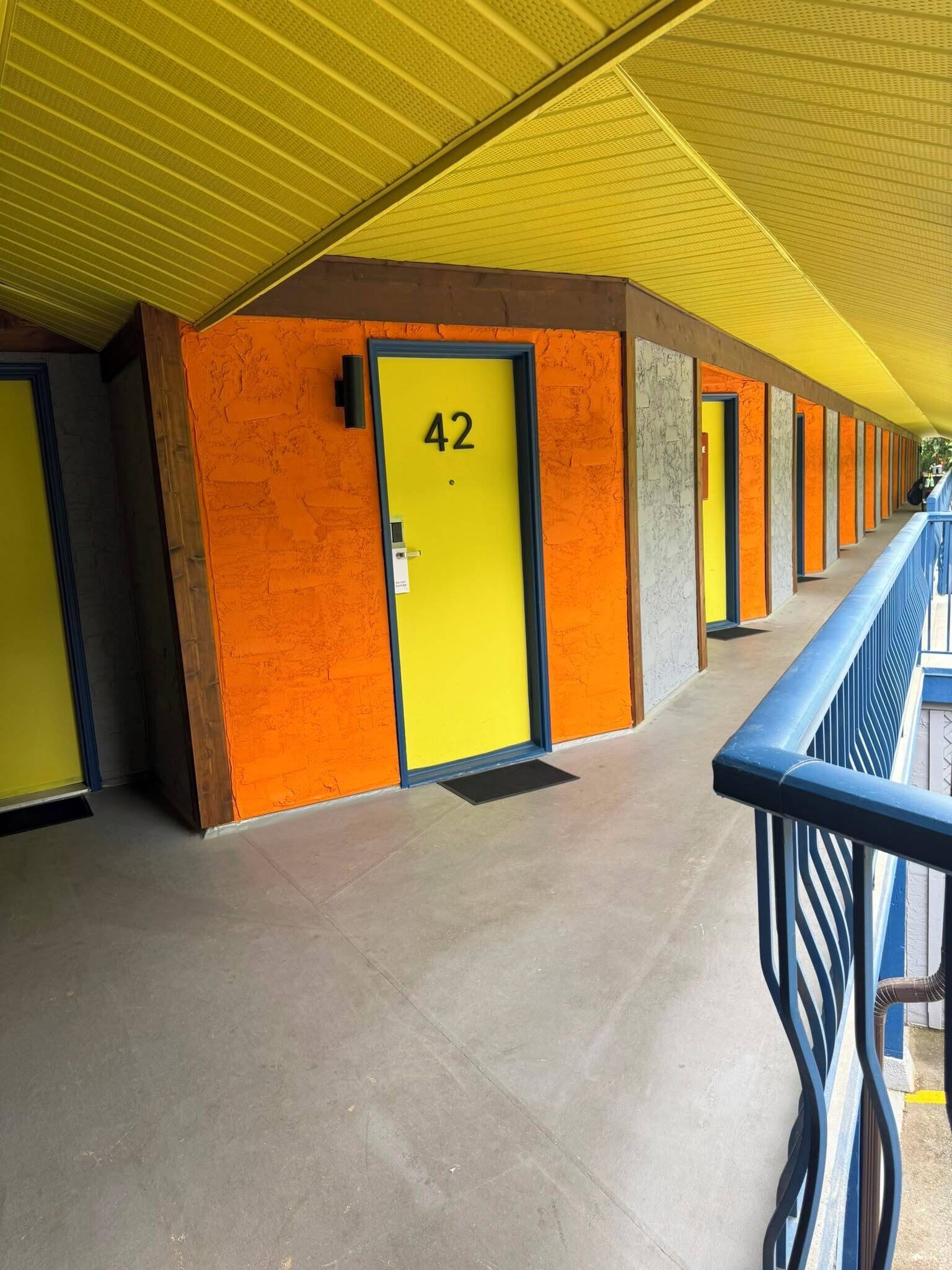 A corridor with doors numbered 42, a yellow ceiling, and a blue railing.