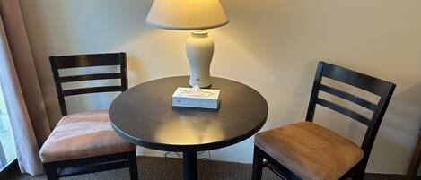 A small round table with a lamp, two chairs, and a tissue box on it.