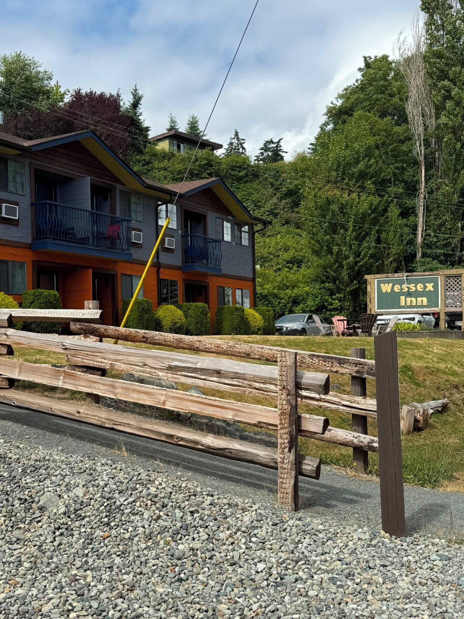 Un edificio de dos pisos con un balcón, un letrero y una valla de madera.