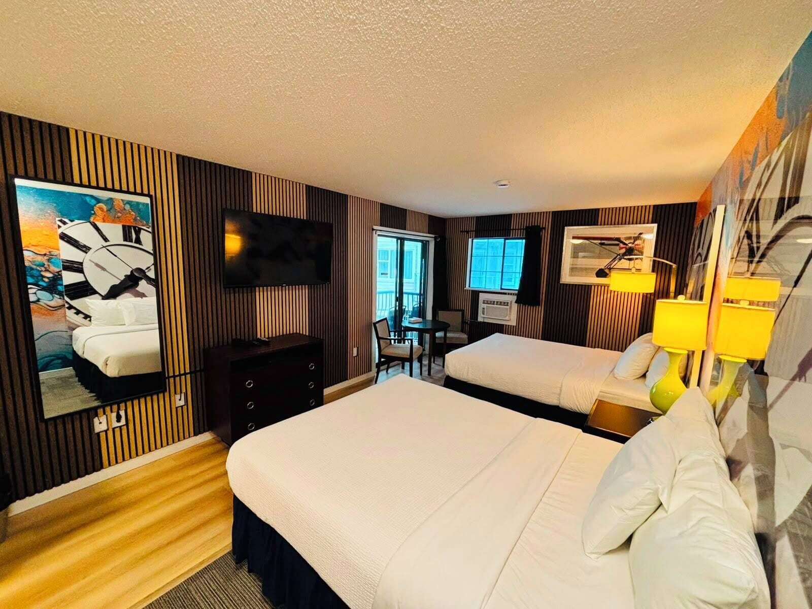 Une chambre d’hôtel avec deux lits, une télévision, un bureau et une grande peinture représentant une horloge au mur.