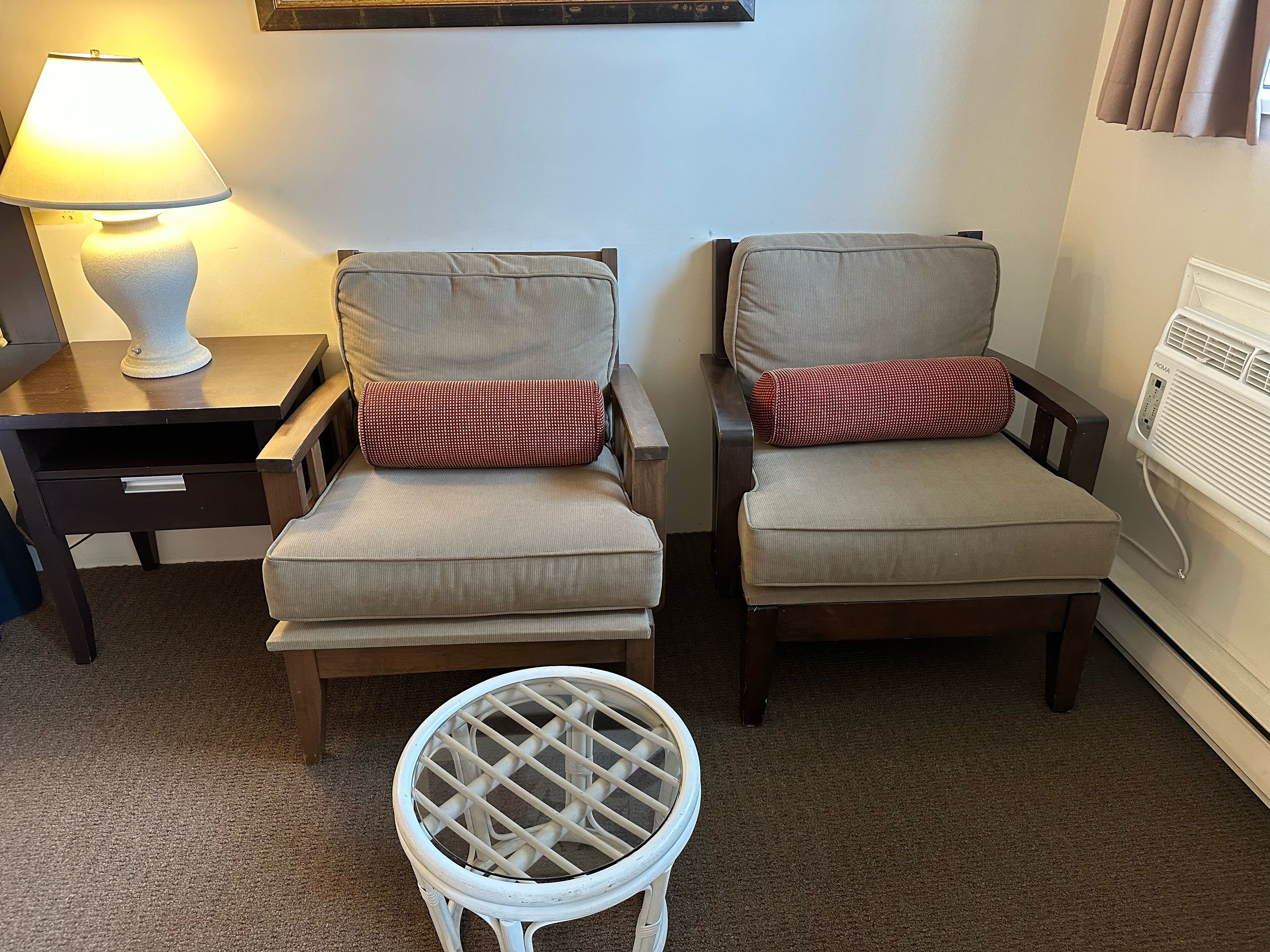Two armchairs with cushions, a small round table, a lamp, and a radiator.