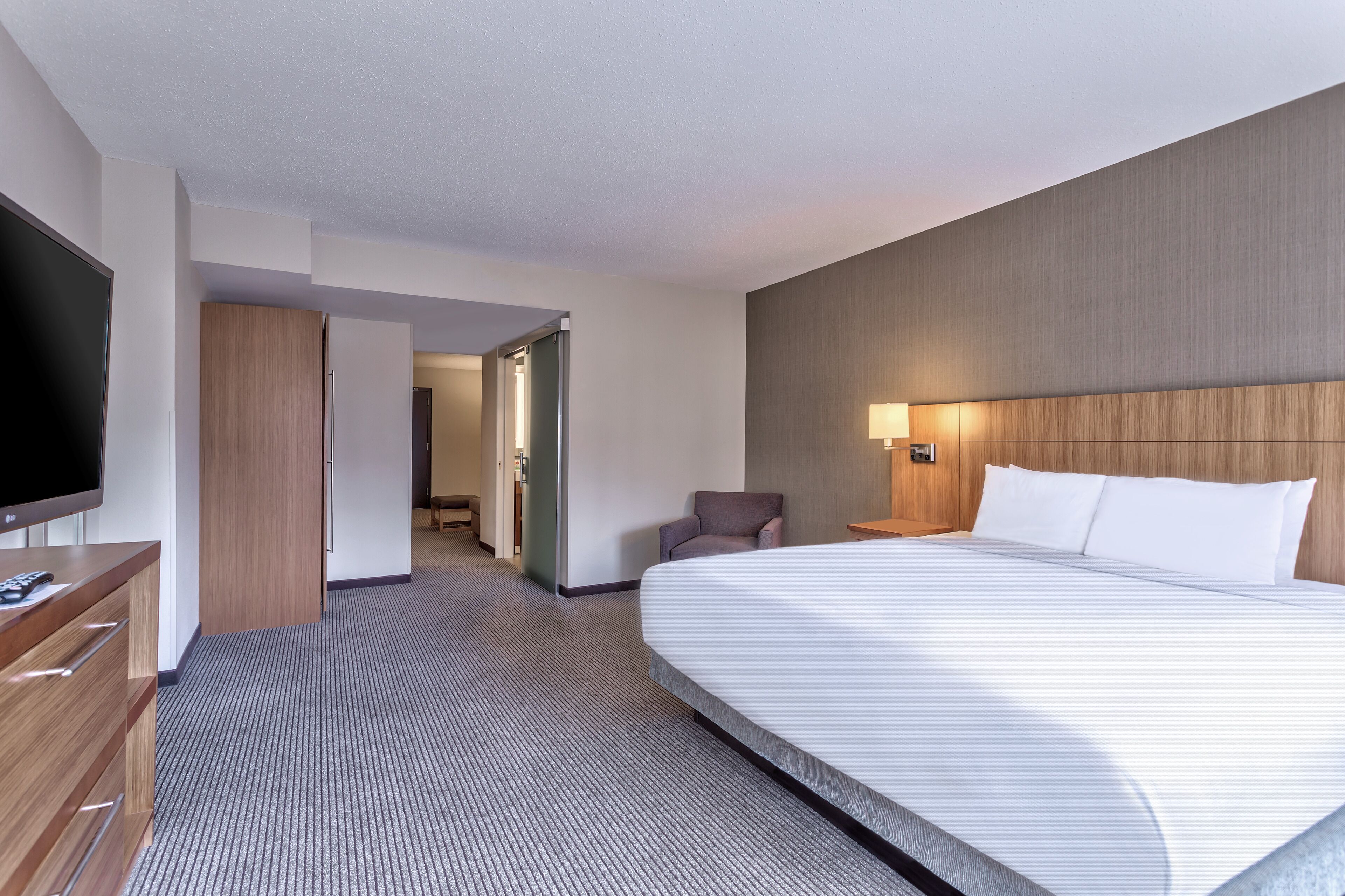 A hotel room with a large bed, a TV, a desk, and a wardrobe.