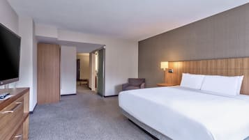 A hotel room with a large bed, a TV, a desk, and a wardrobe.
