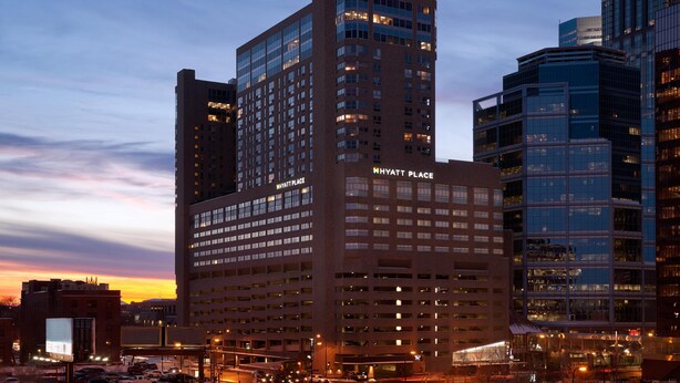 A multi-story hotel with a prominent 'Hyatt Place' sign, surrounded by other buildings.