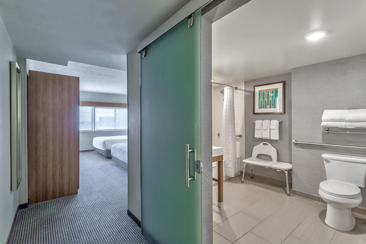Een hotelkamer met een bed, een groene schuifdeur, een douche, toilet en wastafel.