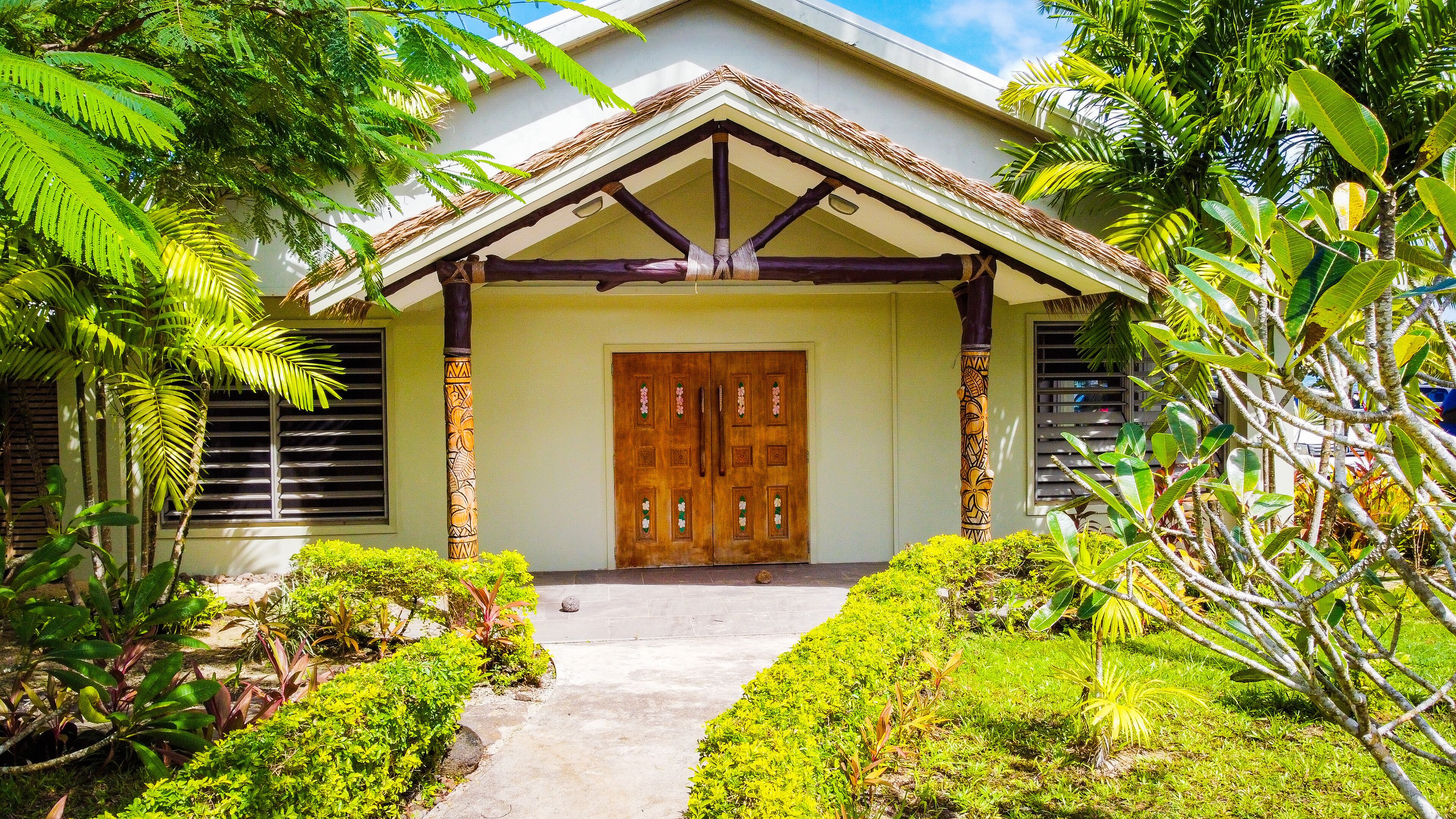 A traditional house with a wooden door, a thatched roof, and a concrete pathway leading to the entrance.