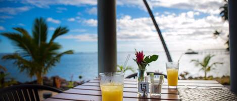 A table with a glass of orange juice, a number 15 sign, and a view of the ocean and palm trees.