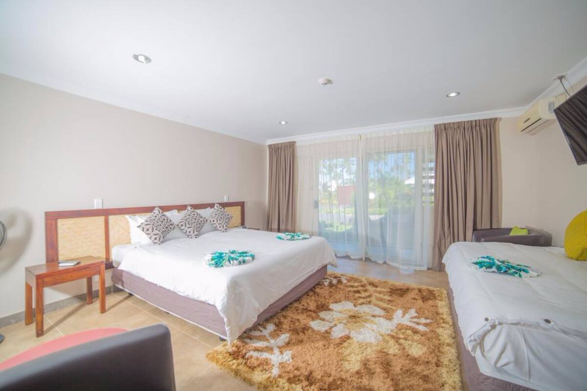 A hotel room with a large bed, a smaller bed, a desk, and a chair.