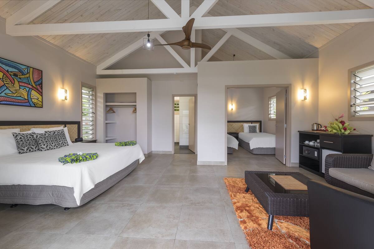 A spacious bedroom with a large bed, a ceiling fan, and a painting on the wall.