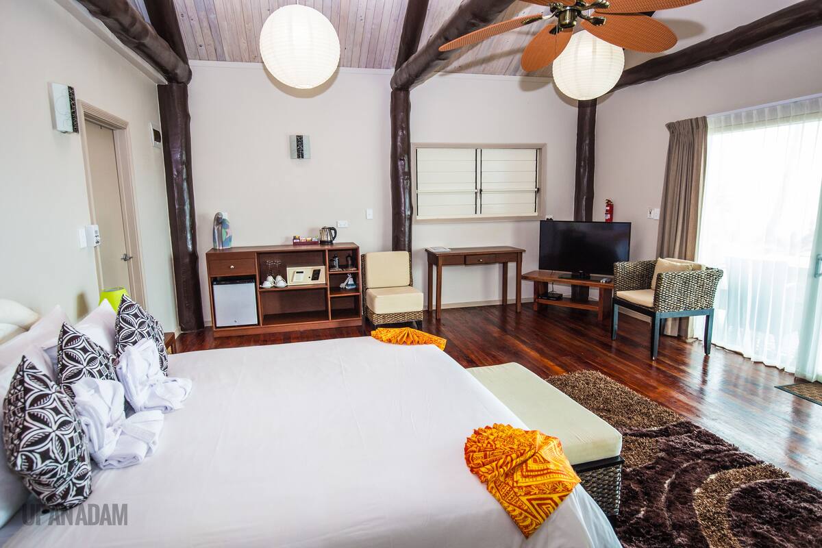 A hotel room with a large bed, a desk, a television, and a chair.
