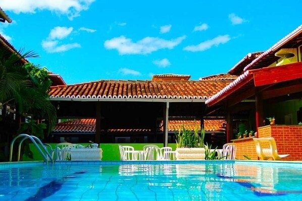 Een buitenzwembad, ligstoelen bij het zwembad