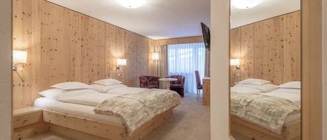 A hotel room with two beds, a small round table, a chair, and a mirror.