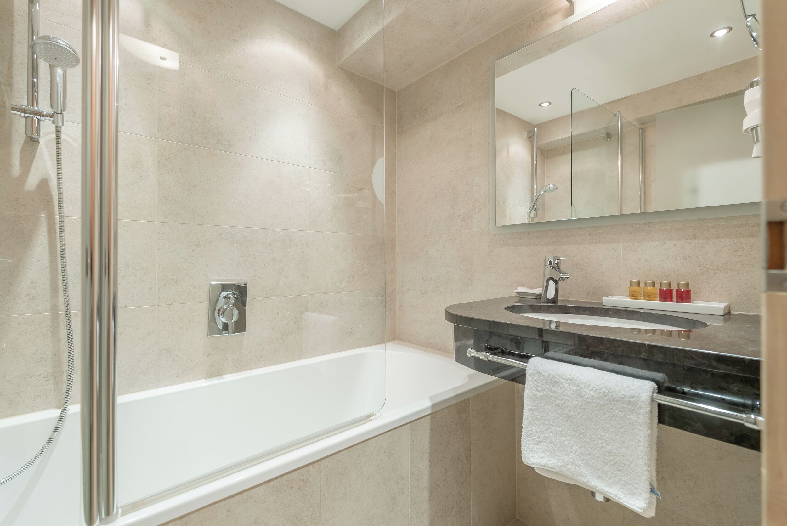 Un baño moderno con ducha de vidrio, bañera independiente y tocador con espejo.