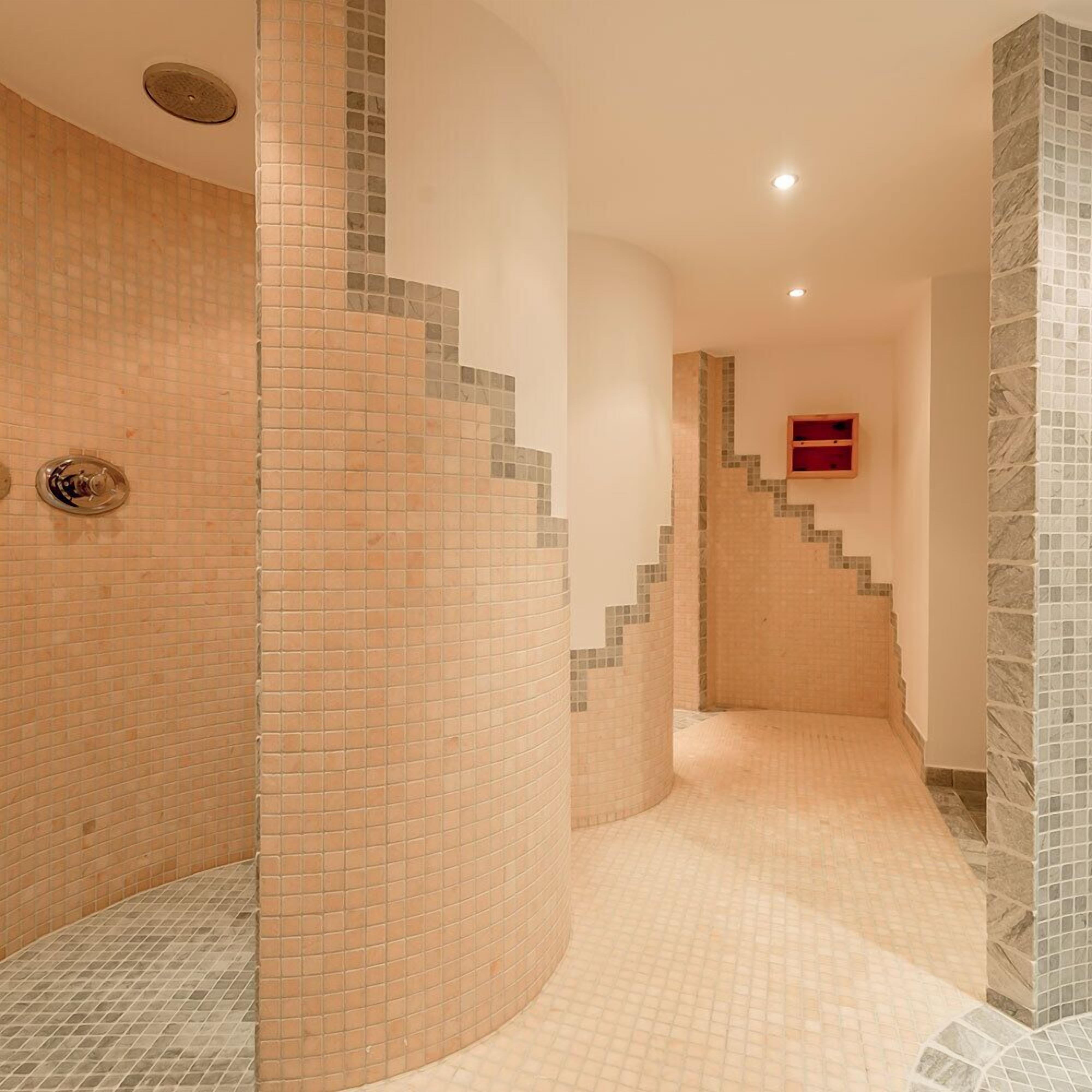 A bathroom with curved walls, tiled flooring, and a built-in shower area.