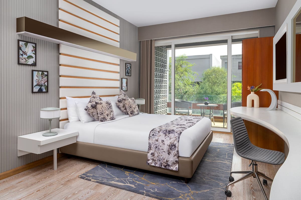 A modern bedroom with a bed, bedside table, and a desk with a chair.