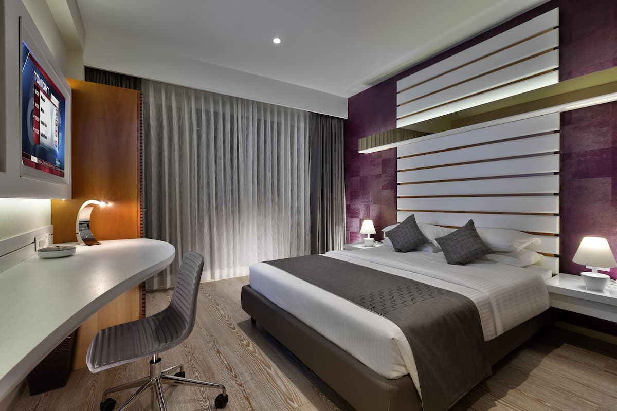 A modern hotel room with a large bed, a desk, and a chair.