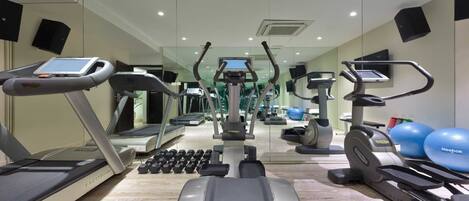 Une salle de sport équipée de tapis de course, de vélos elliptiques et de poids libres.