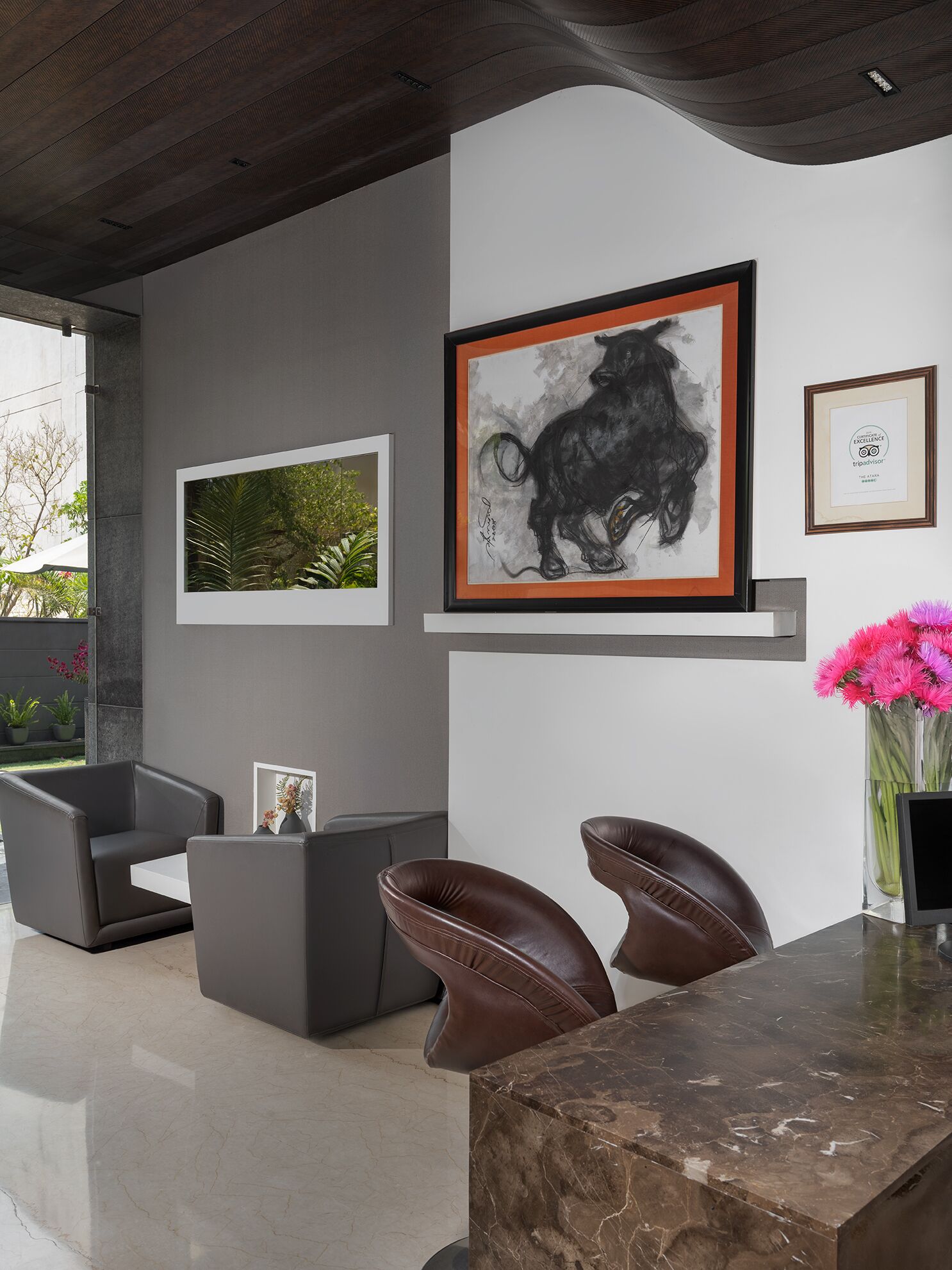 A modern interior with a marble countertop, leather chairs, and framed artwork on the wall.