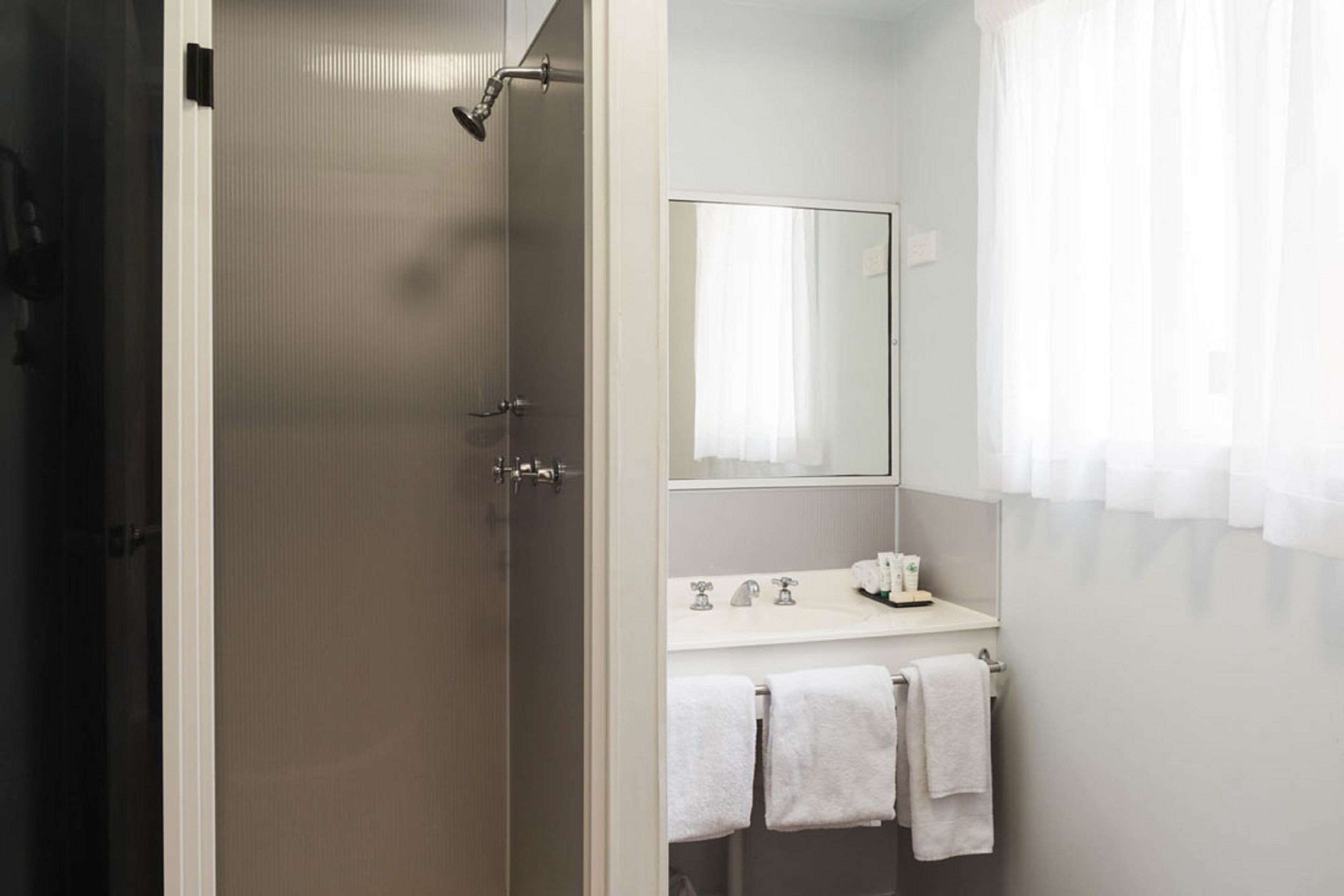 A bathroom with a shower, a sink, and a mirror.