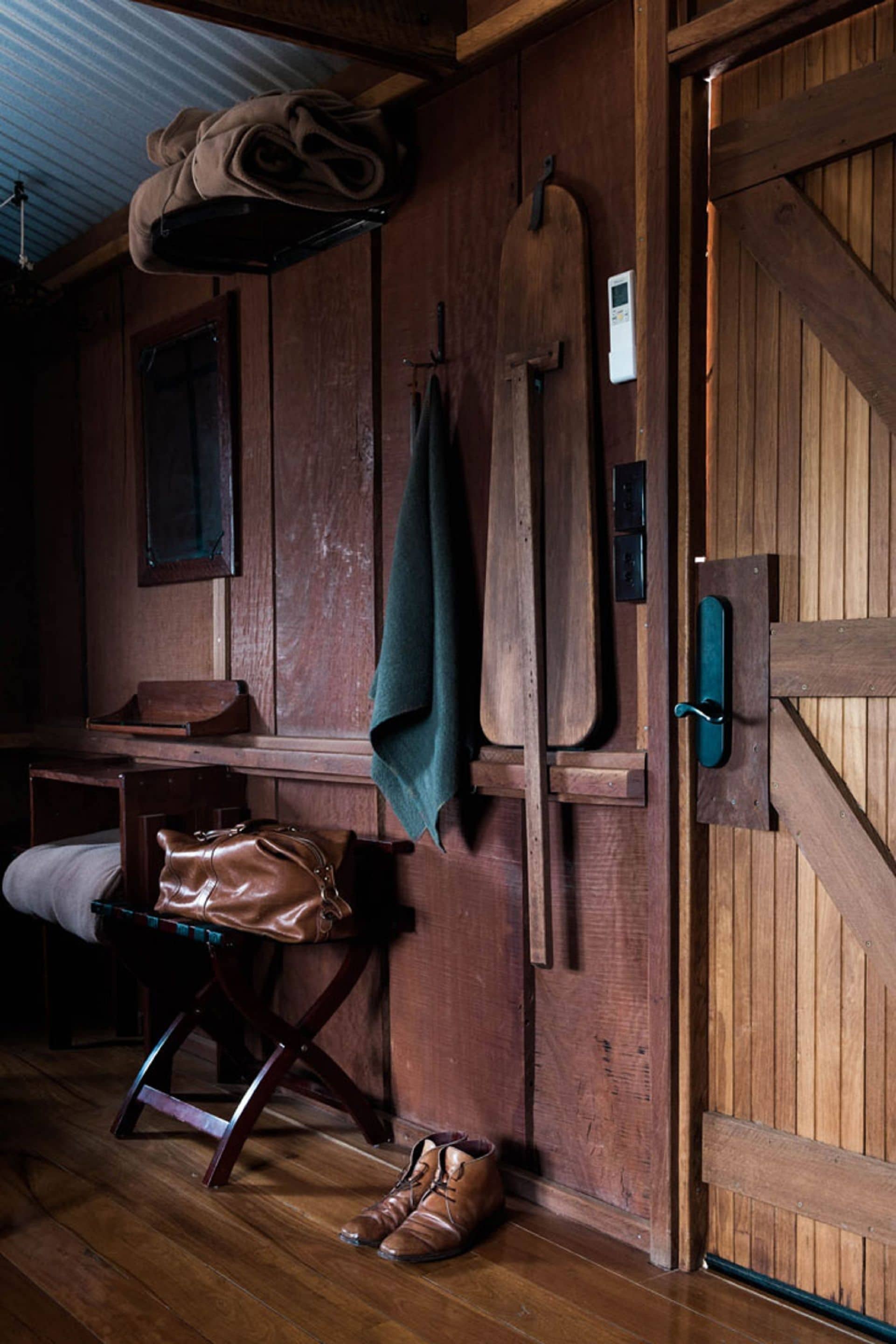 Een eenvoudige kamer met houten wanden, een bank, kapstok en een deur.