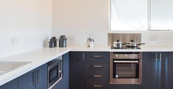 Una cocina moderna con armarios oscuros, horno empotrado y microondas.