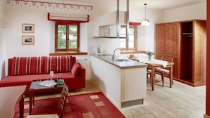 Un espacio habitable compacto con kitchenette, comedor y un sofá rojo.