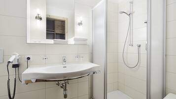 Une salle de bain moderne avec un lavabo blanc, un miroir et une douche à parois de verre.