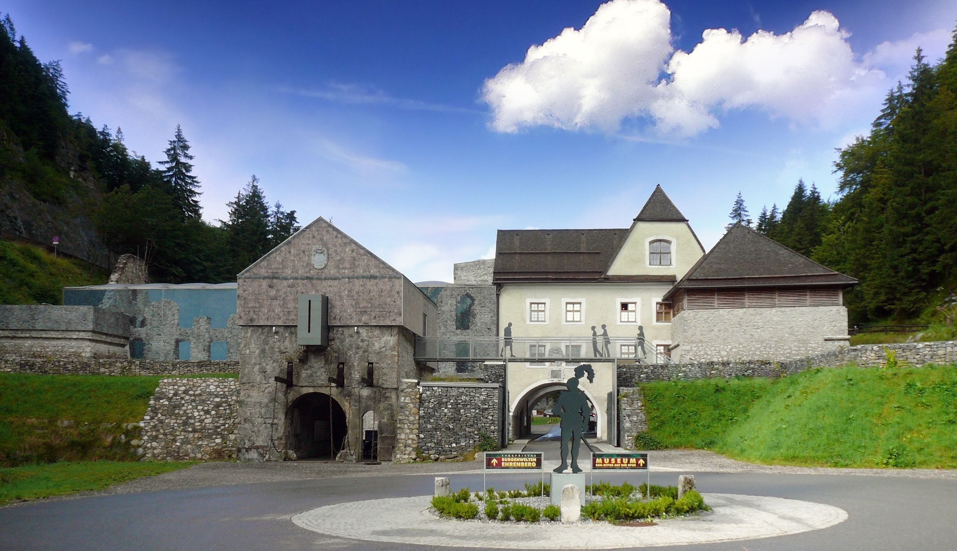 A historic building with stone walls, a central archway, and a museum sign.
