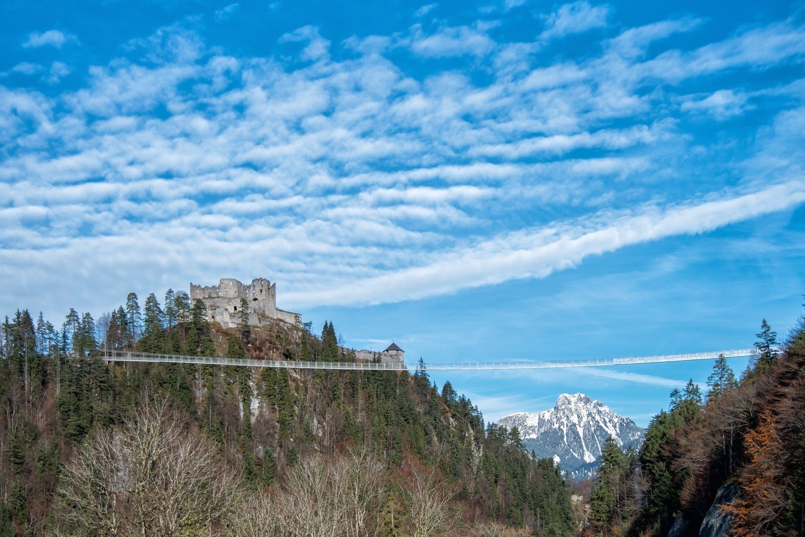 Un castillo histórico en una colina, con un puente al fondo.