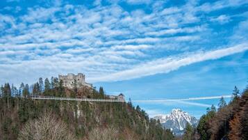 Un castillo histórico en una colina, con un puente al fondo.