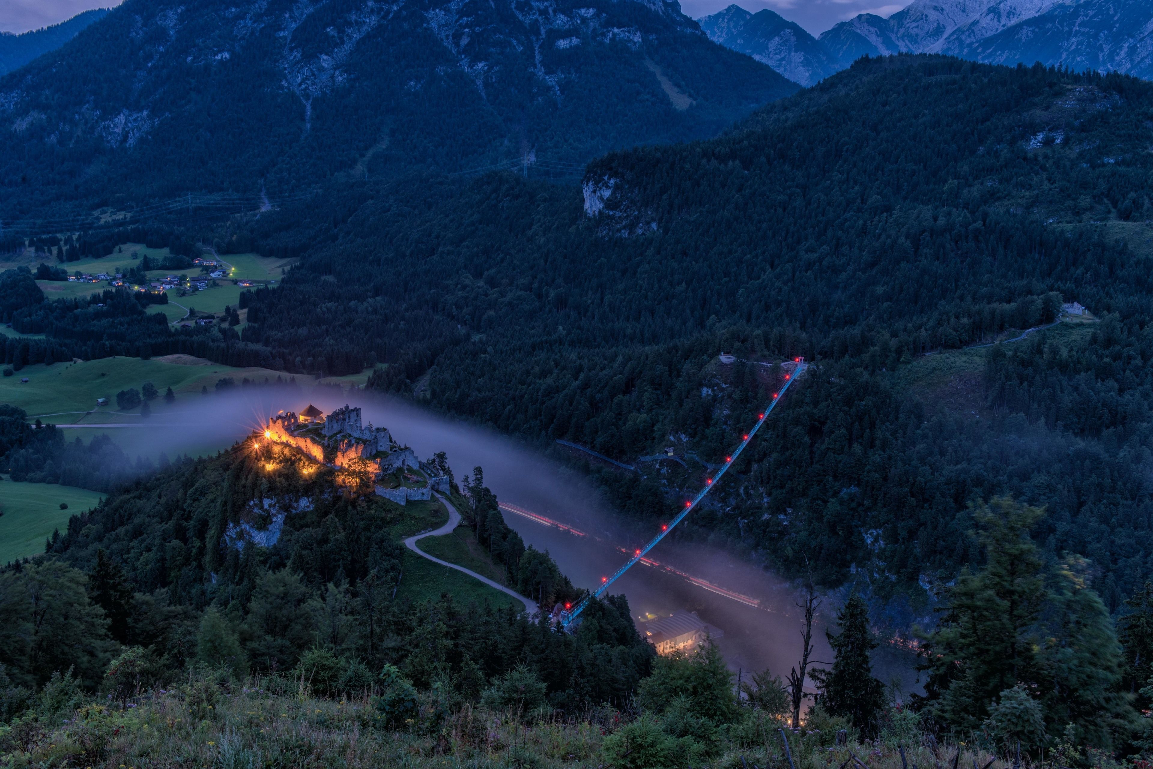 A mountain landscape with a winding road and a castle-like structure on a hill.