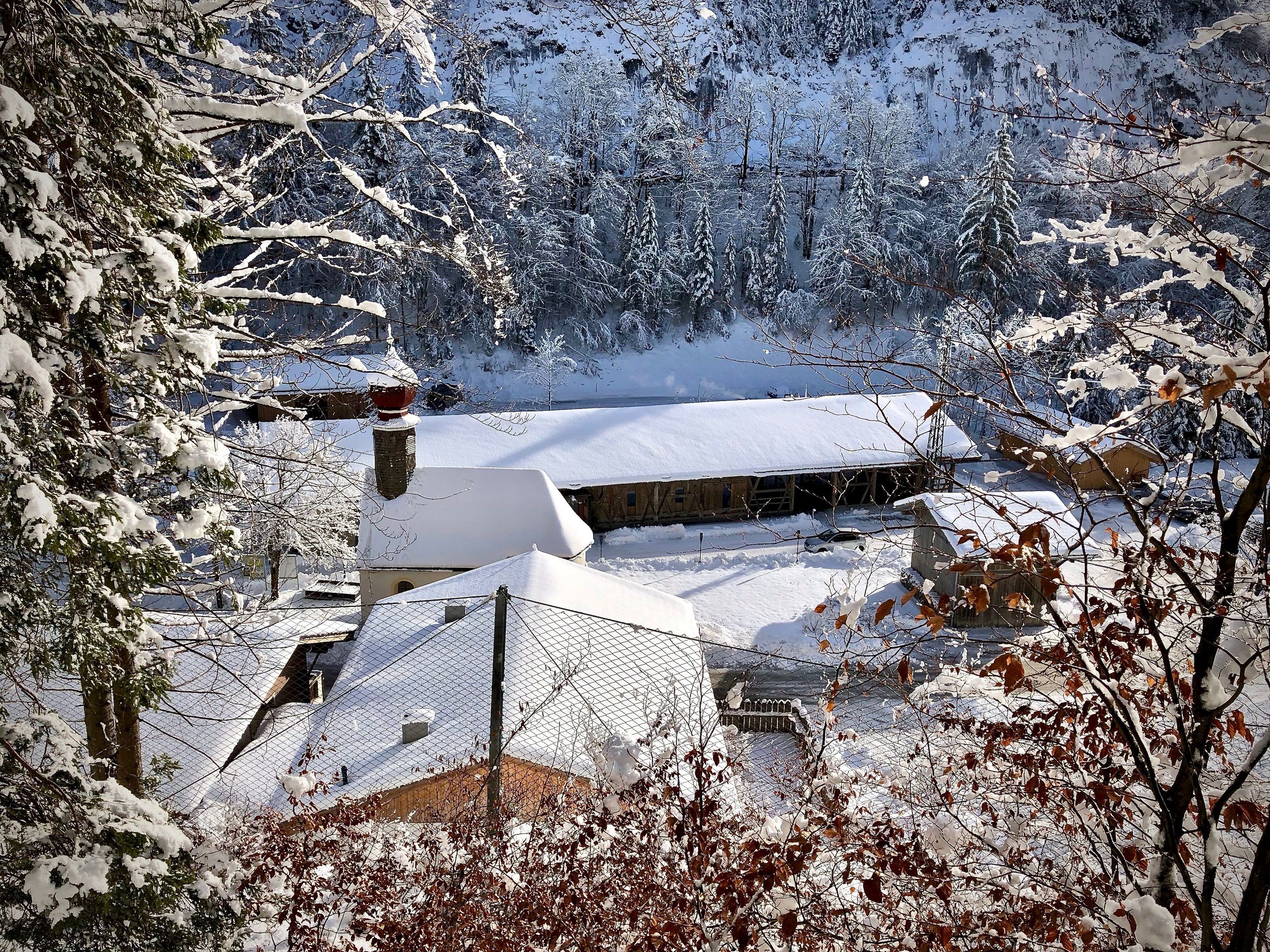 Un paysage enneigé avec une maison et une zone délimitée par une clôture.