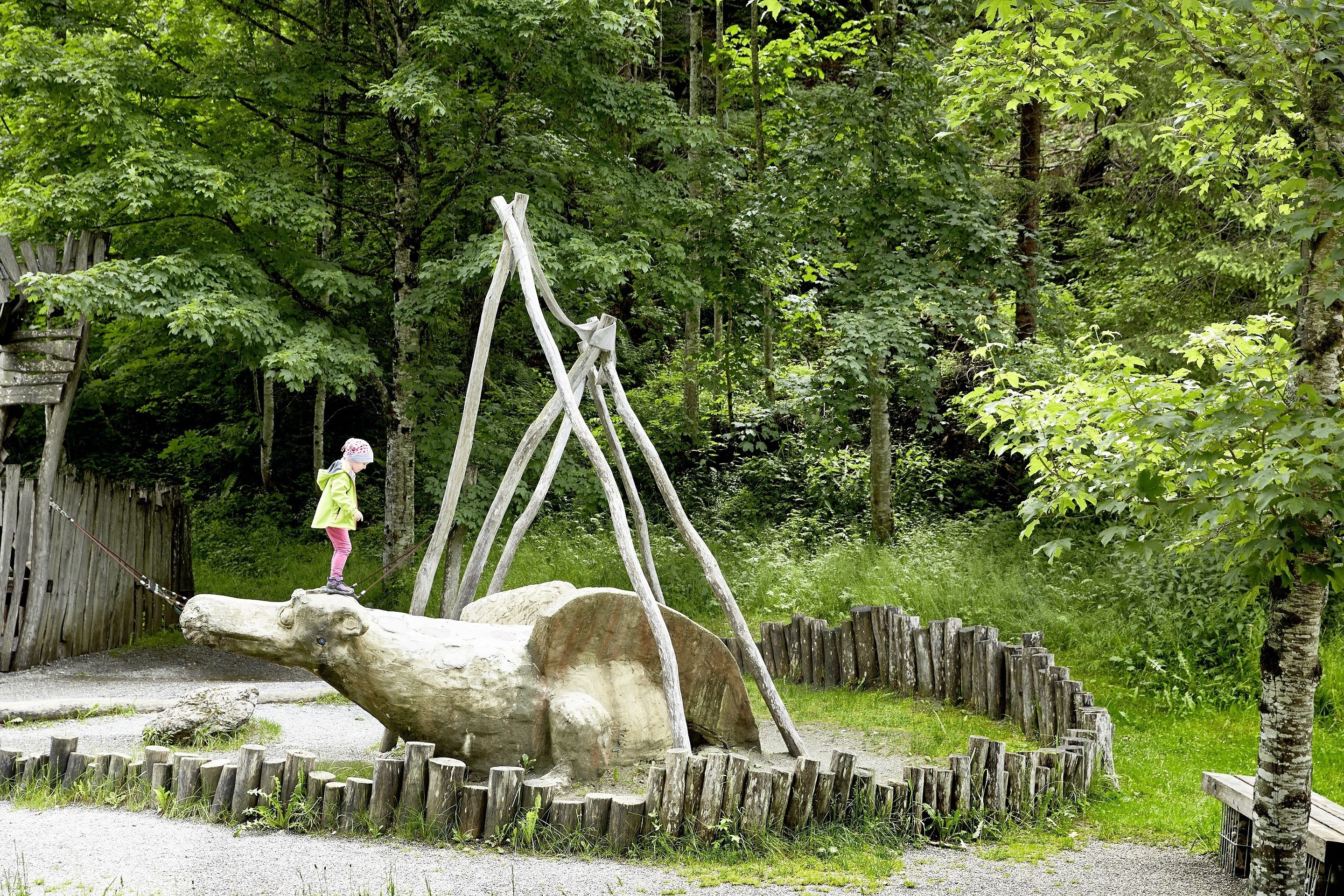 Una escultura de madera de un animal grande en un área boscosa.