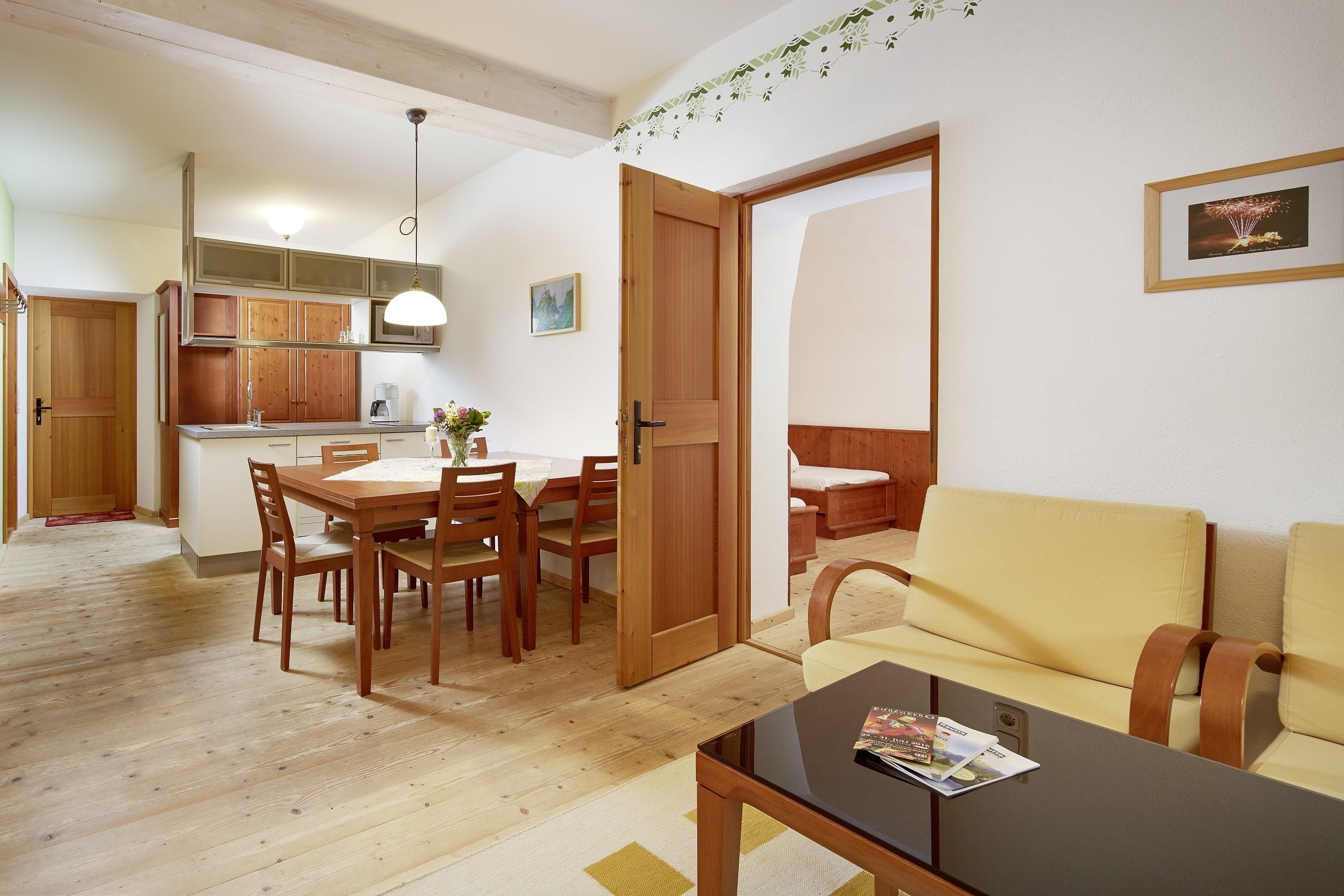 A compact living space with a dining area, a sofa, and a kitchen in the background.