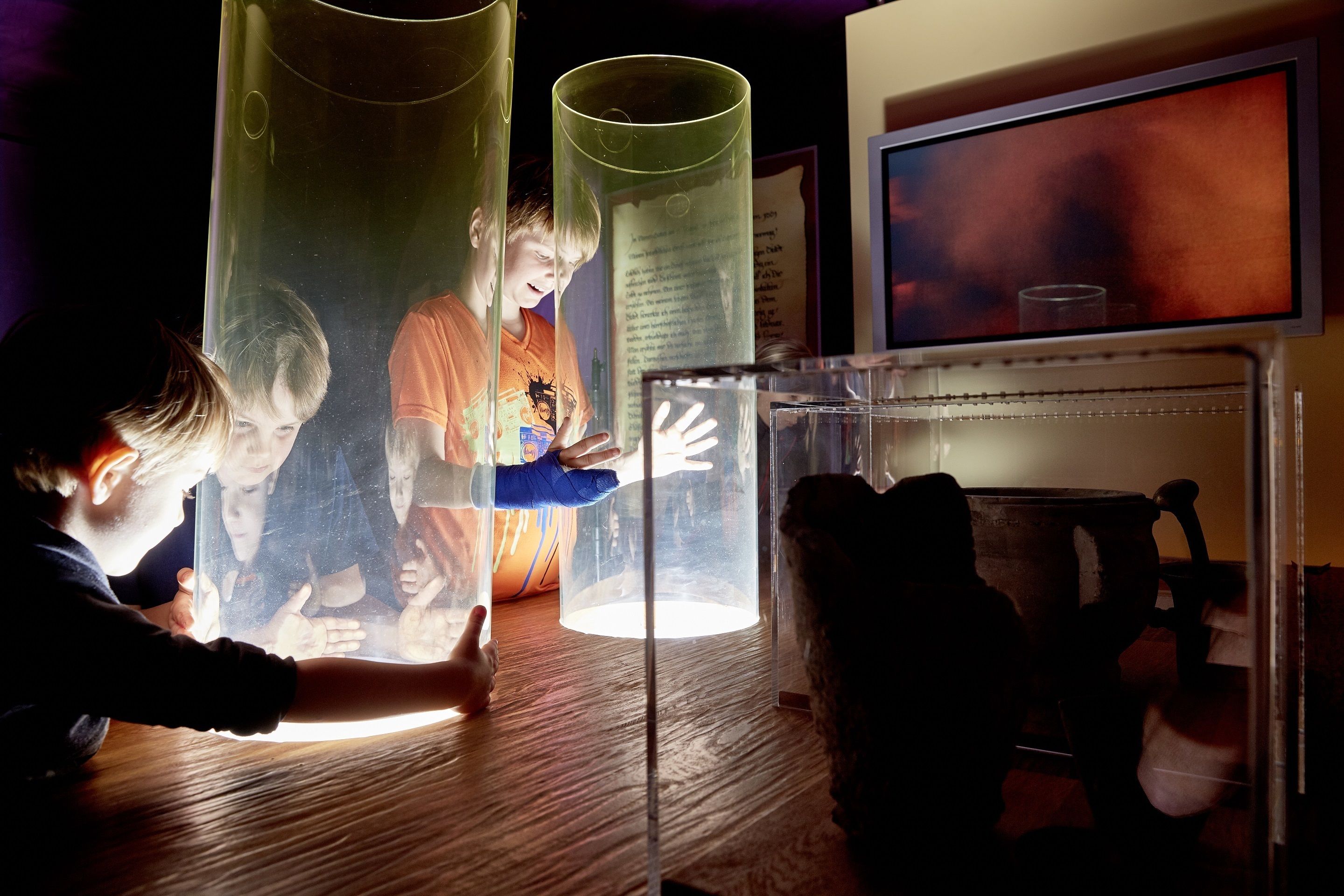 A room with a wooden floor, a transparent cylindrical object, and a chair.