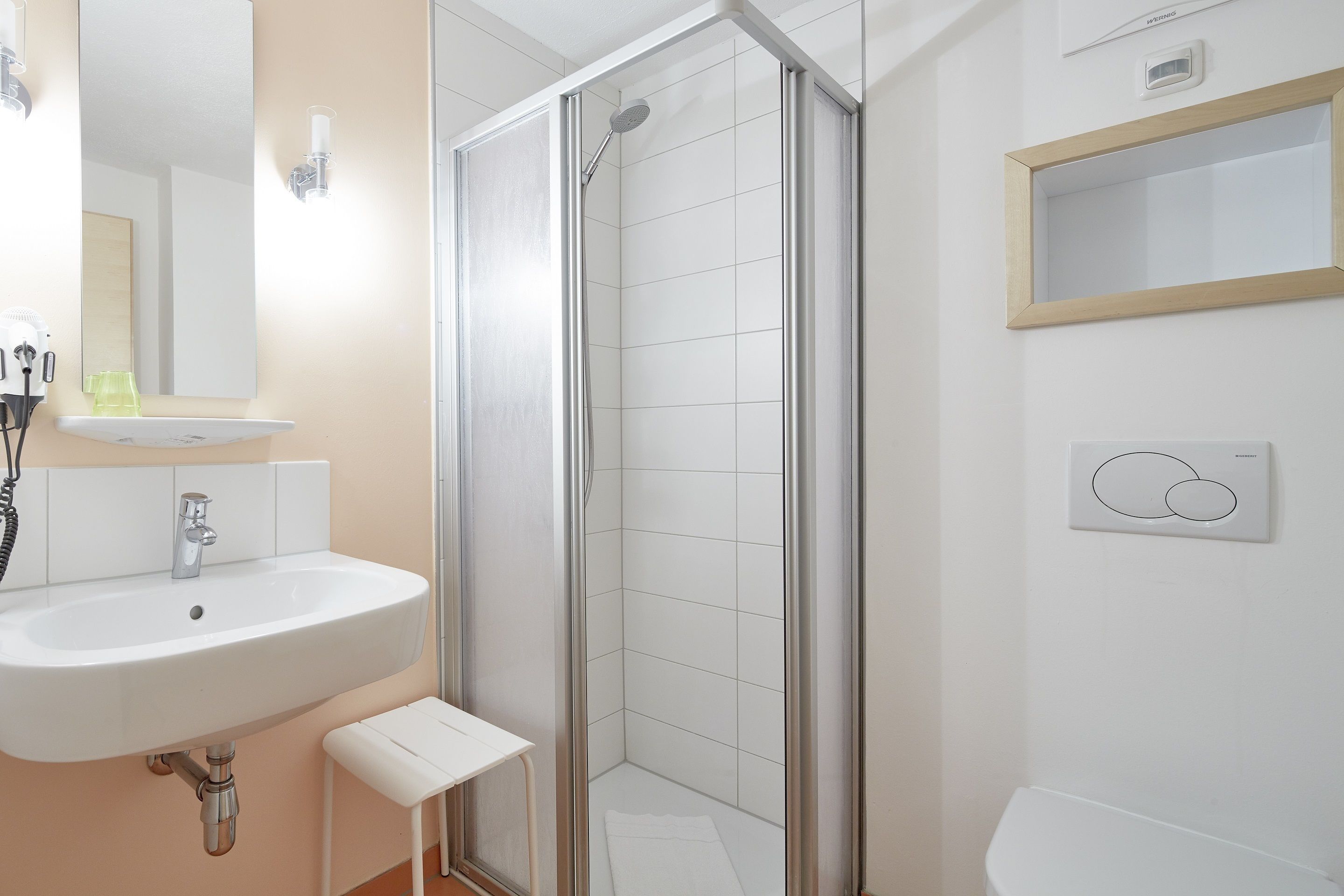 A bathroom with a sink, mirror, shower, and toilet.