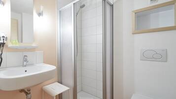 A bathroom with a sink, mirror, shower, and toilet.