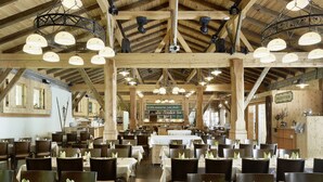 Un restaurante espacioso con altos techos de madera, varias mesas para comer y una zona de recepción.
