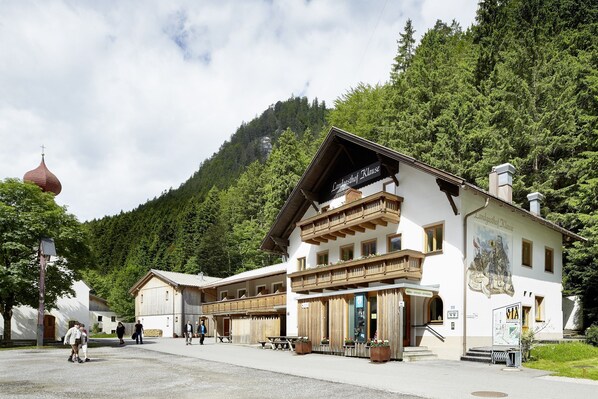 A traditional building with a balcony, a sign reading "Landgasthof Klaus," and a mural depicting historical figures. - Gasthof Salzstadl (Reutte)